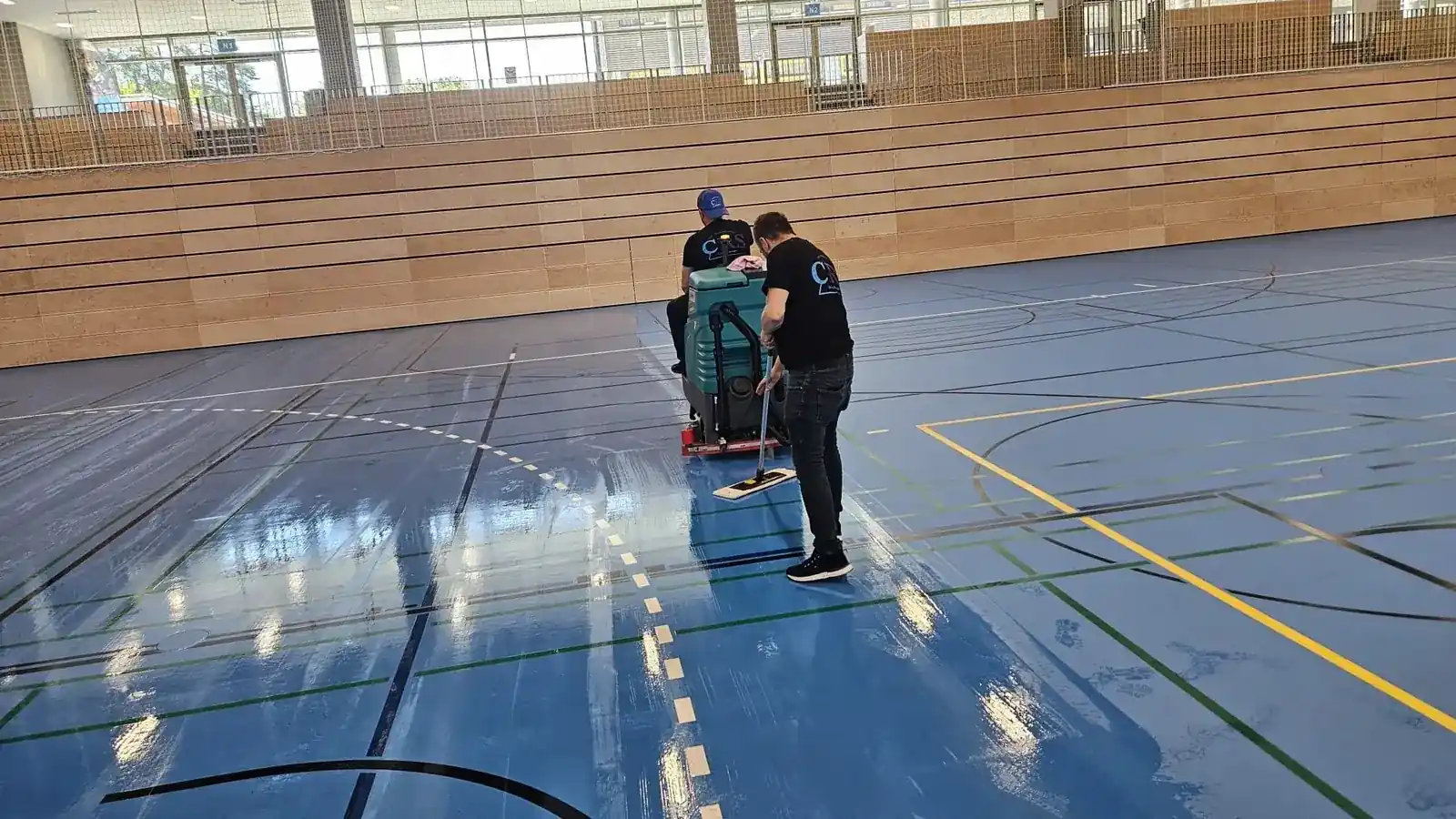 CRS-Mitarbeiter reinigen einen Hallenboden mit der Scheuersaugmaschine