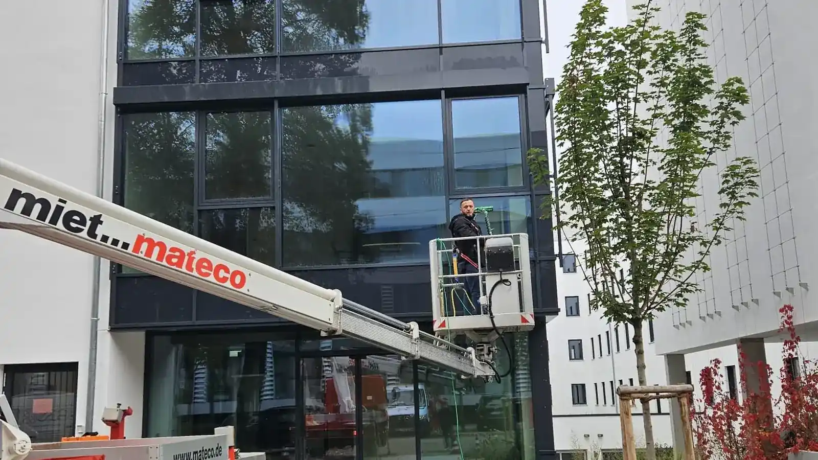 Mitarbeiter reinigt eine Glasfassade von der Hebebühne aus